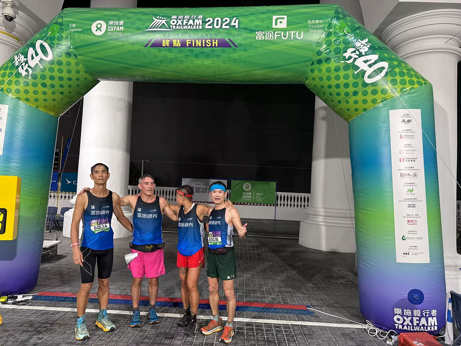 Jo’s team under the Oxfam Trailwalker 2024 finish arch at night